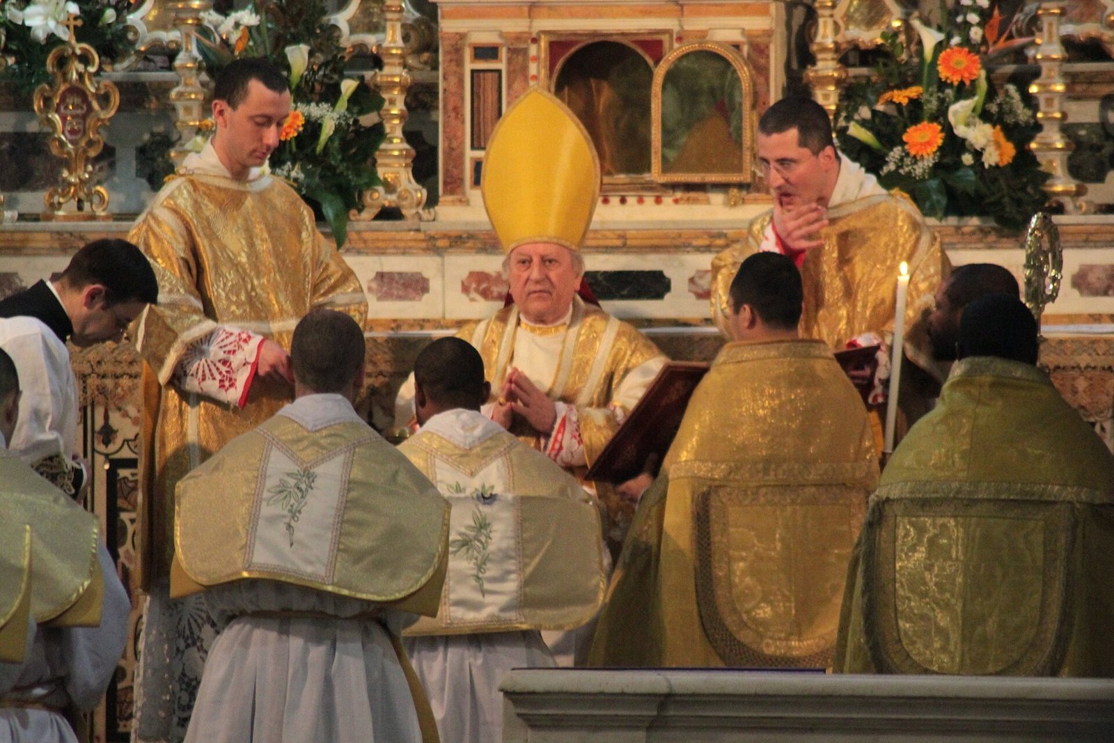 Bispo impõe as mãos sobre candidatos durante cerimônia de ordenação sacerdotal