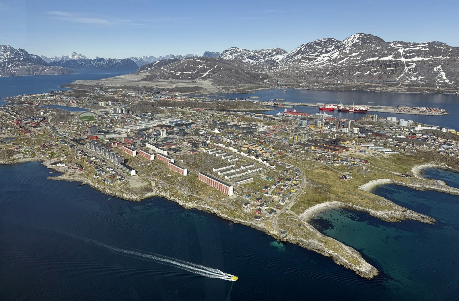 Vista aérea de Nuuk, capital da Groenlândia, com casas, porto e montanhas com neve ao fundo