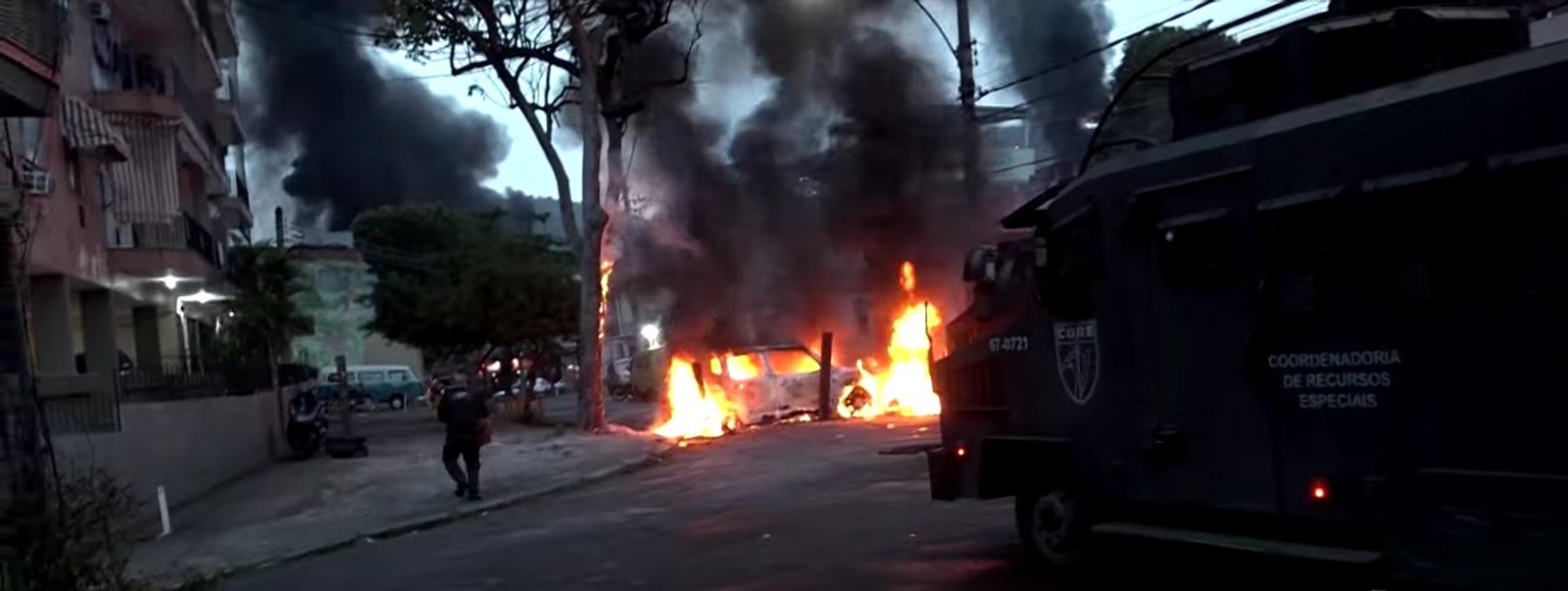 Veículo blindado do Core e carro em chamas em rua do Rio durante a Operação Contenção, em 2025
