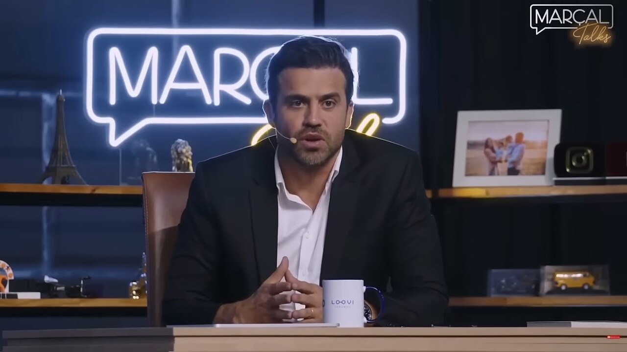 Pablo Marçal fala ao microfone sentado à bancada do estúdio de seu programa