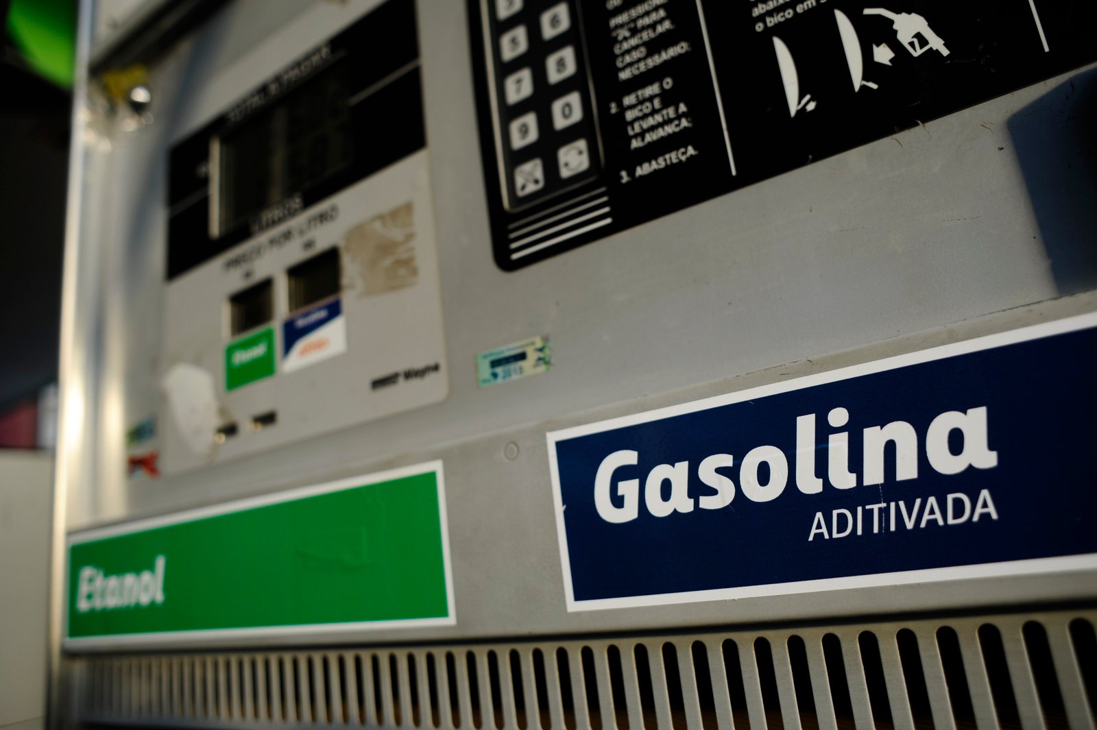 Bomba de combustível em posto de gasolina com placas de gasolina aditivada e etanol