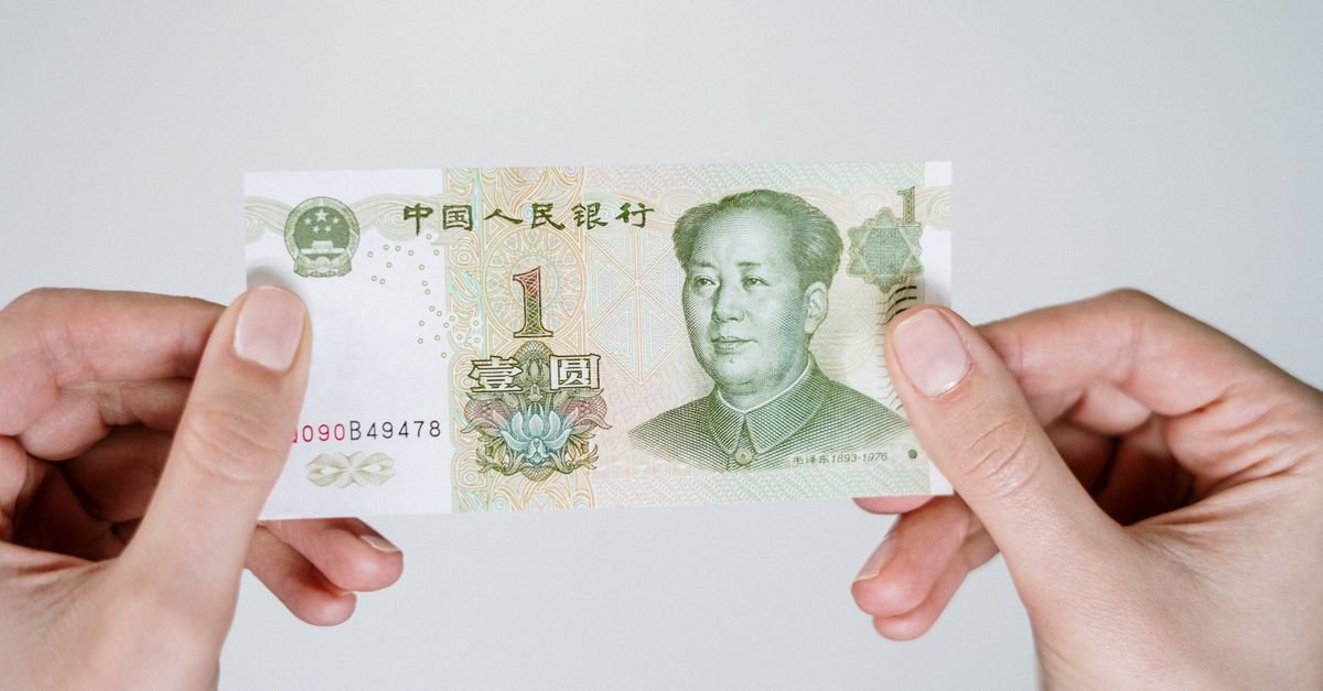 Mãos seguram uma cédula de um yuan, moeda oficial da China
