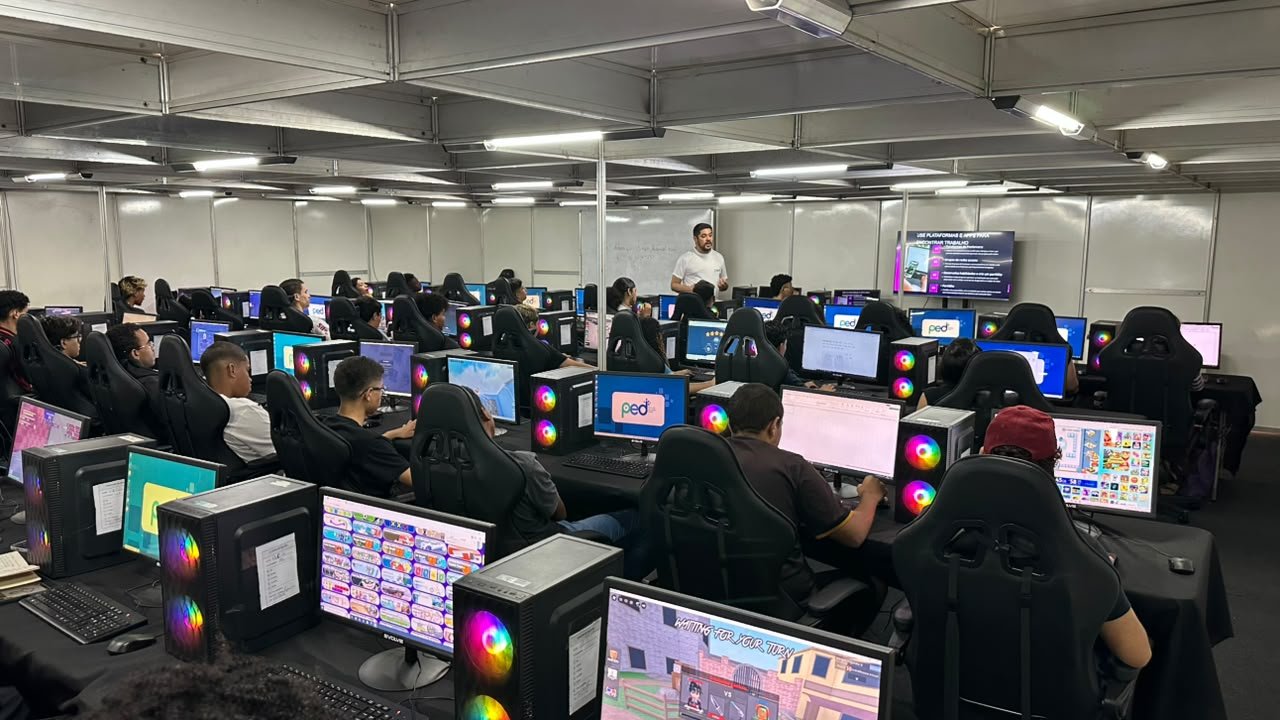 Sala do PED com alunos em computadores e telão com o tema 'use plataformas e apps para encontrar trabalho'