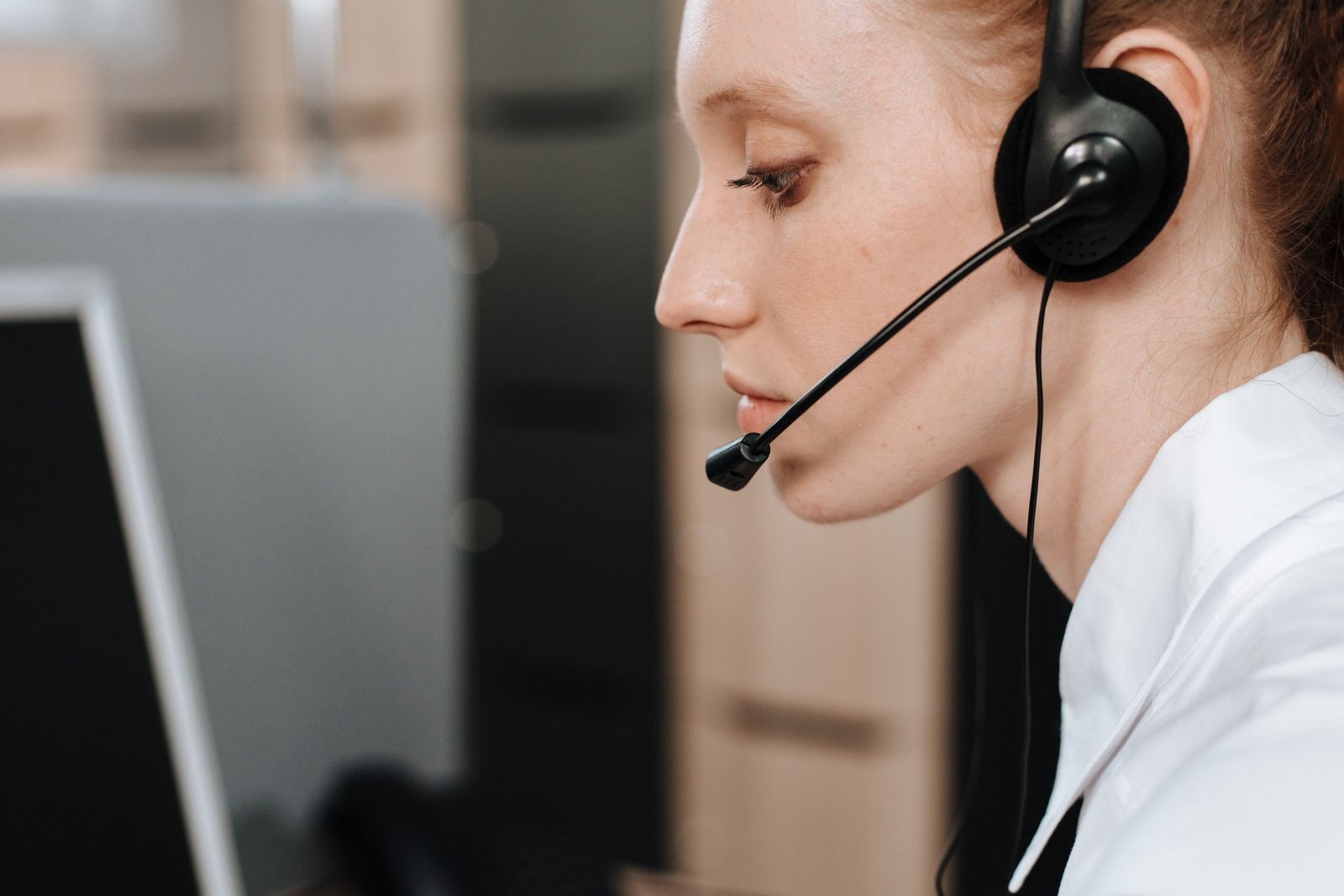 Entrevistadora de call center com fone de ouvido diante do computador, imagem ilustrativa de pesquisa por telefone