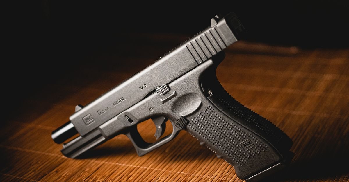 Pistola preta apoiada sobre superfície de bambu em ambiente escuro