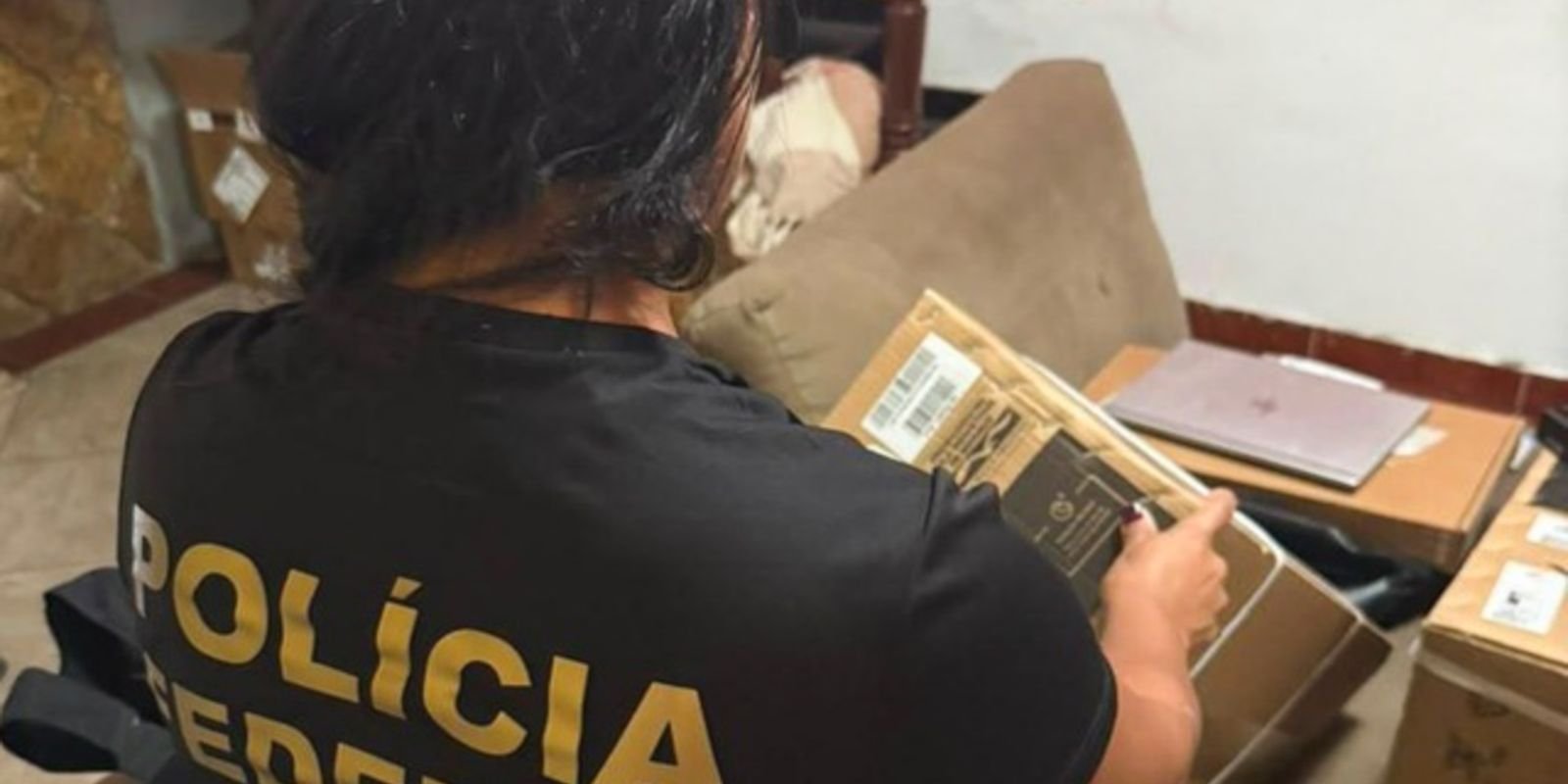 Agente da Polícia Federal examina encomendas e caixas apreendidas durante operação