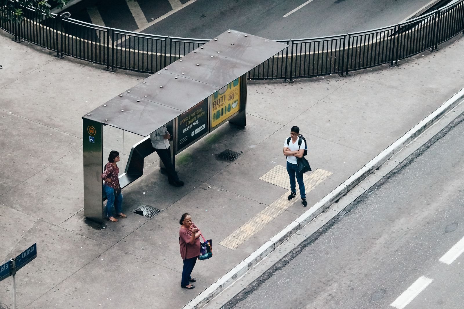 Vista aérea de passageiros esperando em um ponto de ônibus coberto numa avenida de São Paulo (foto de arquivo)