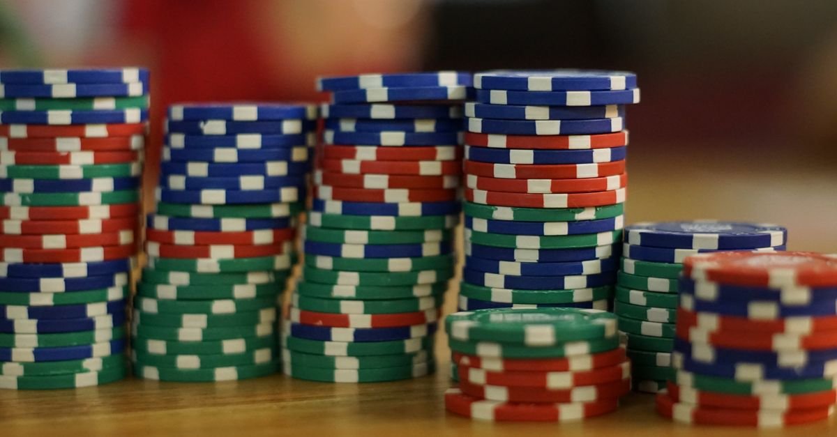Pilhas de fichas de jogo azuis, verdes e vermelhas sobre uma mesa de madeira