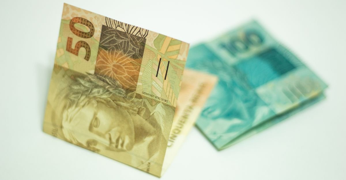 Cédulas brasileiras de 50 e 100 reais sobre fundo branco