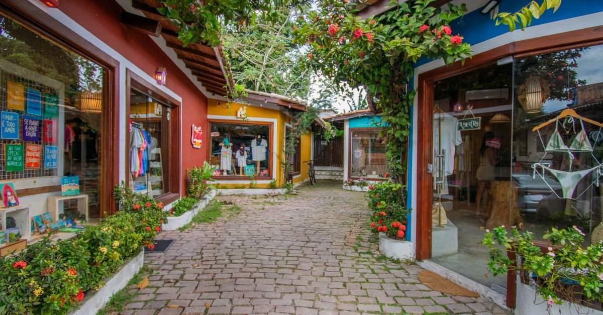 Rua de comércio com pequenas lojas coloridas e placa de aberto em cidade brasileira