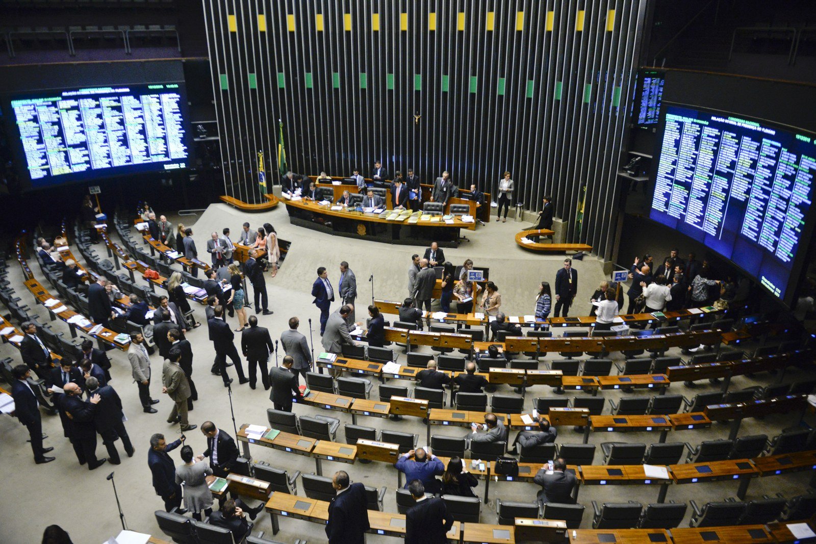 Plenário da Câmara dos Deputados em sessão, com deputados conversando no centro e painéis de presença (foto de arquivo de 2016)