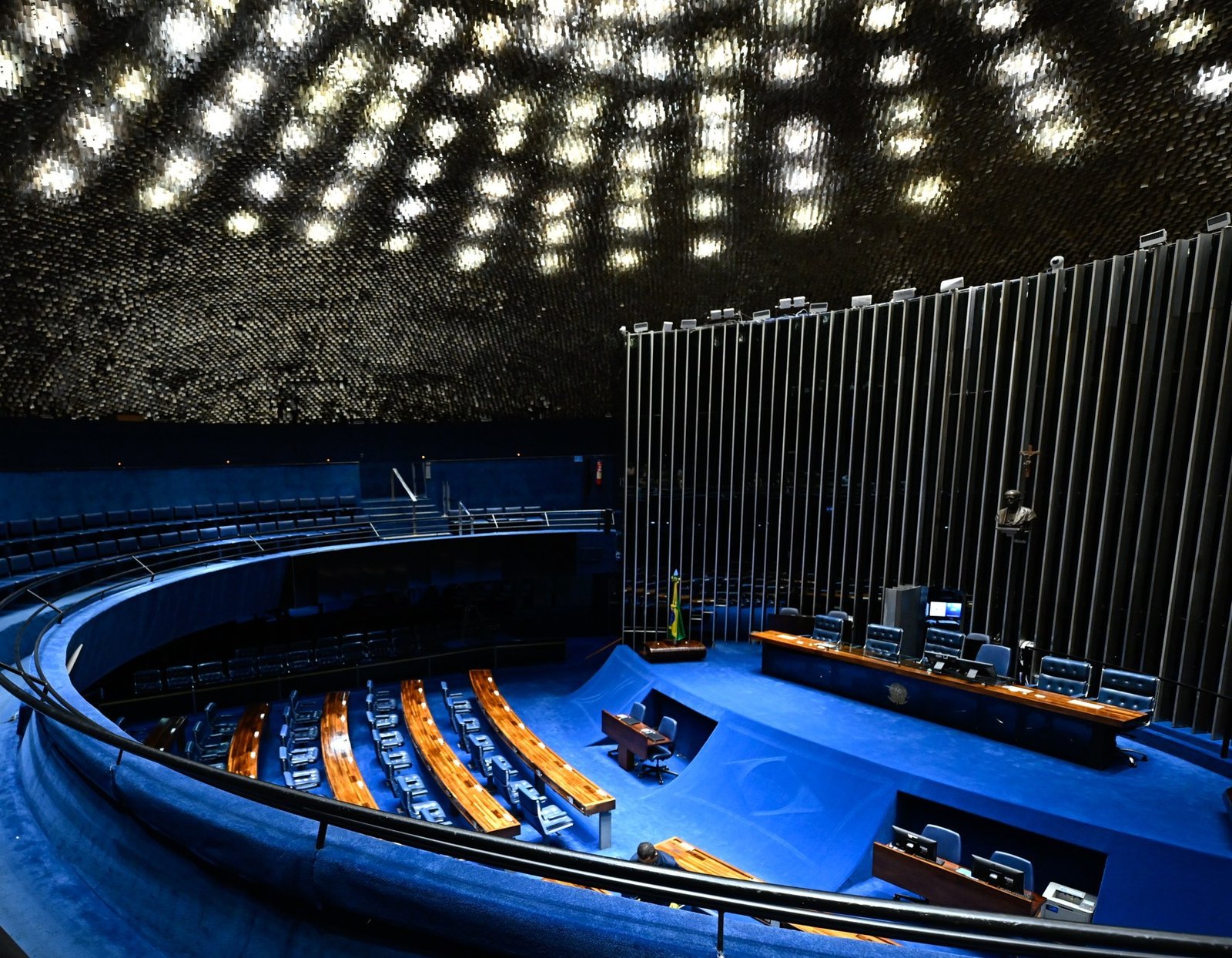 Plenário do Senado Federal visto da galeria, com a cúpula iluminada, a mesa diretora e as bancadas vazias
