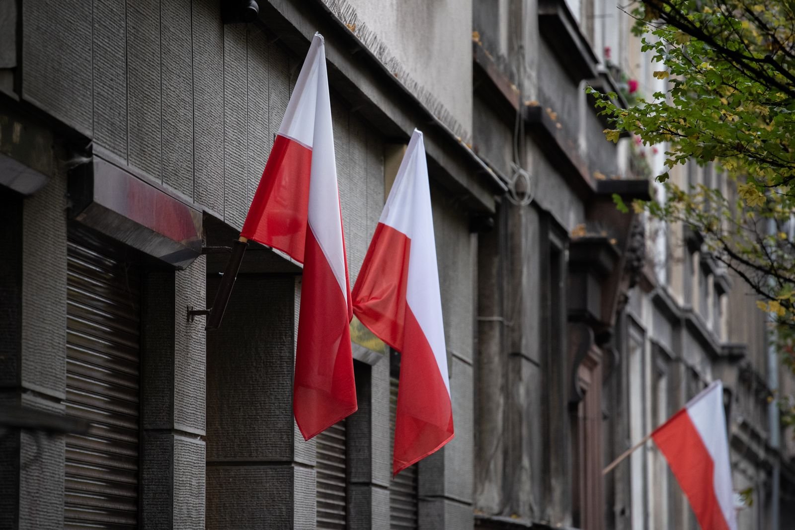 Bandeiras da Polônia penduradas na fachada de um prédio em rua europeia, foto de arquivo