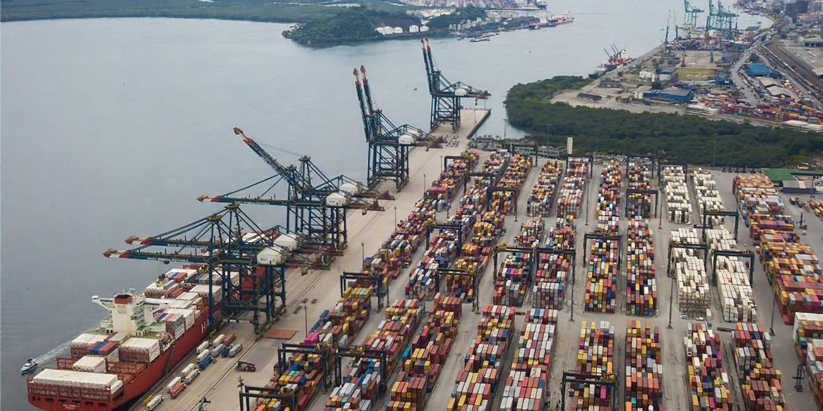 Vista aerea do Porto de Santos com navio atracado, guindastes e patios de conteineres