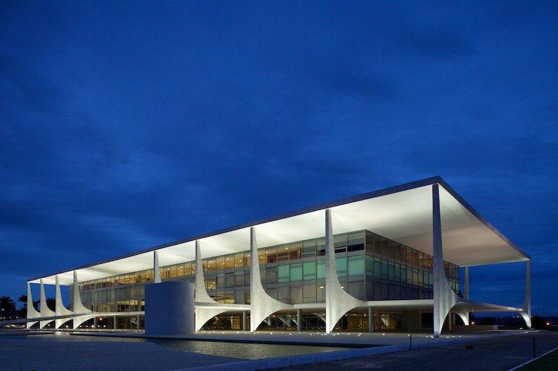 Fachada iluminada do Palacio do Planalto, em Brasilia, ao anoitecer, com o espelho dagua a frente