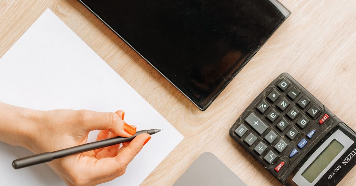 Calculadora, folha de papel em branco e caneta sobre mesa de escritório