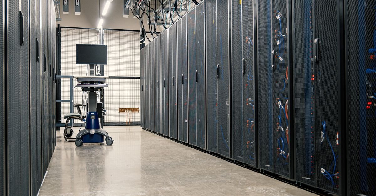 Corredor de data center com racks de servidores e cabeamento de rede