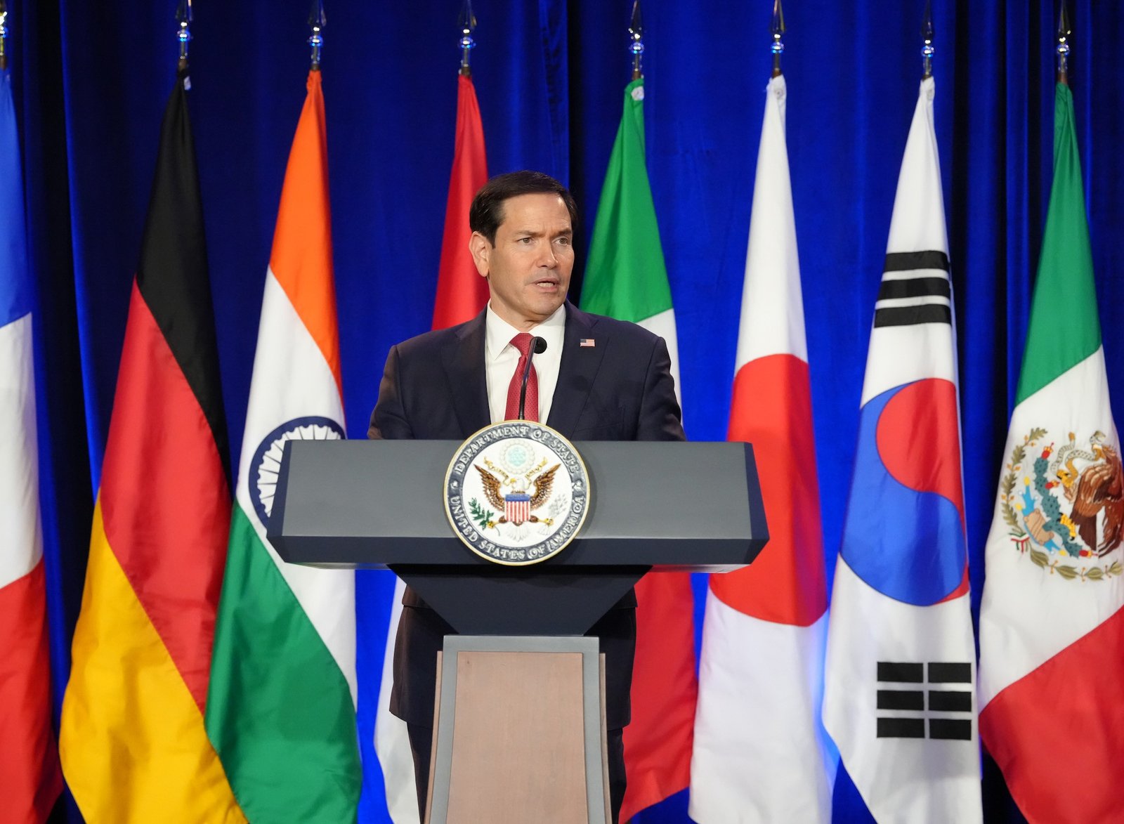 Marco Rubio discursa em púlpito do Departamento de Estado diante de bandeiras de países do G20, em Atlanta