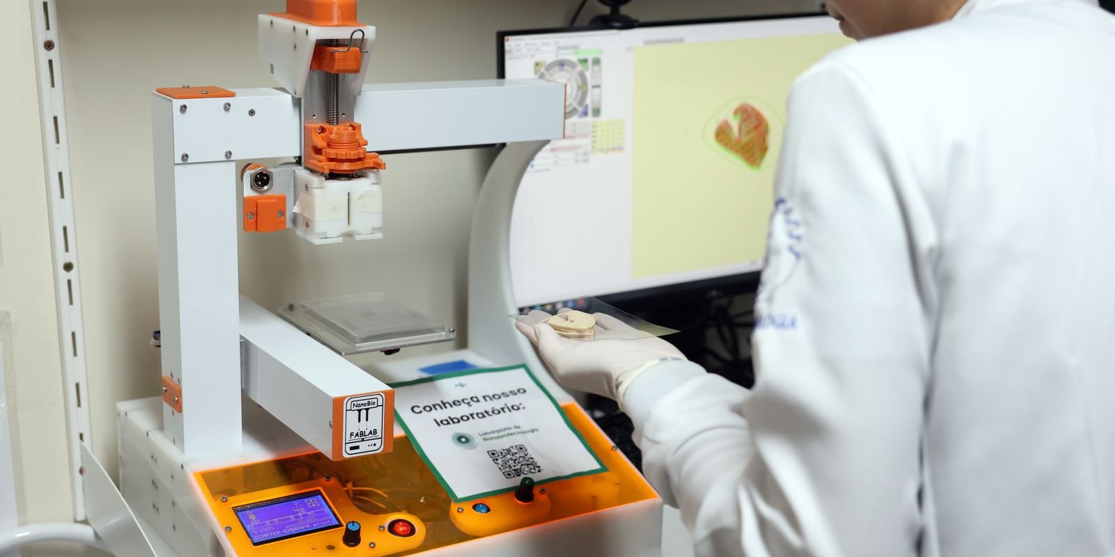 Pesquisadora de jaleco branco opera equipamento de laboratório de nanobiotecnologia