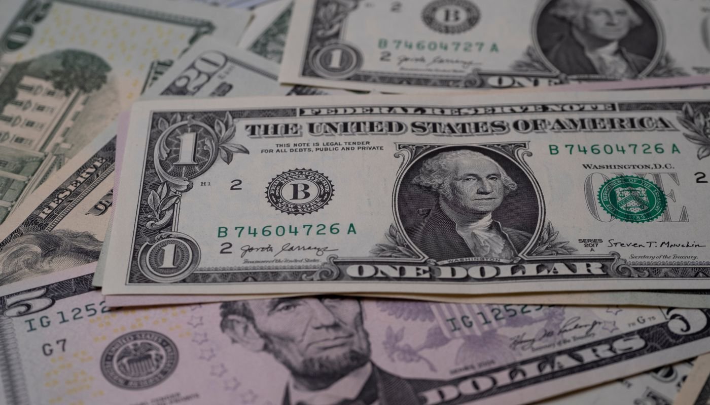 Notas de dólar dos Estados Unidos espalhadas sobre superfície escura