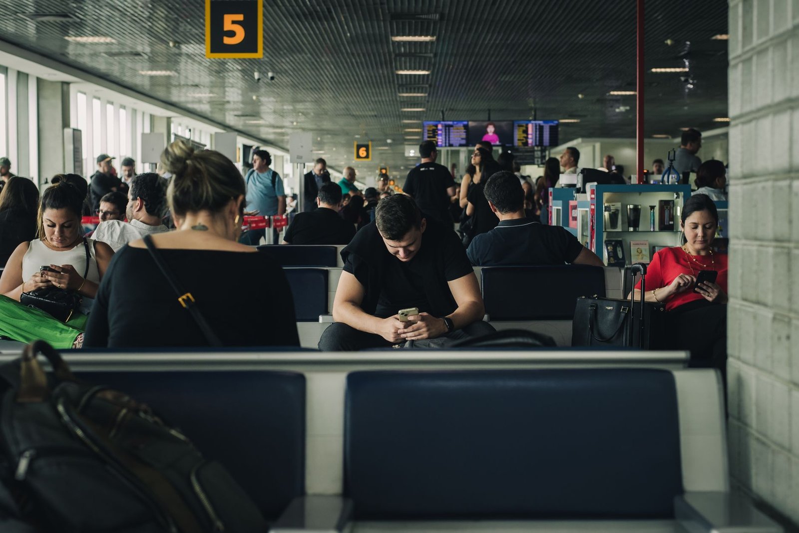 Passageiros sentados em sala de embarque de aeroporto movimentado