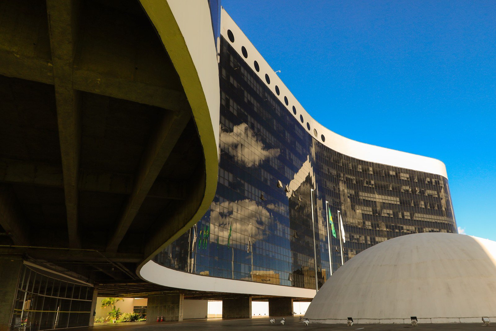 Fachada curva de vidro da sede do Tribunal Superior Eleitoral, em Brasília, sob céu azul