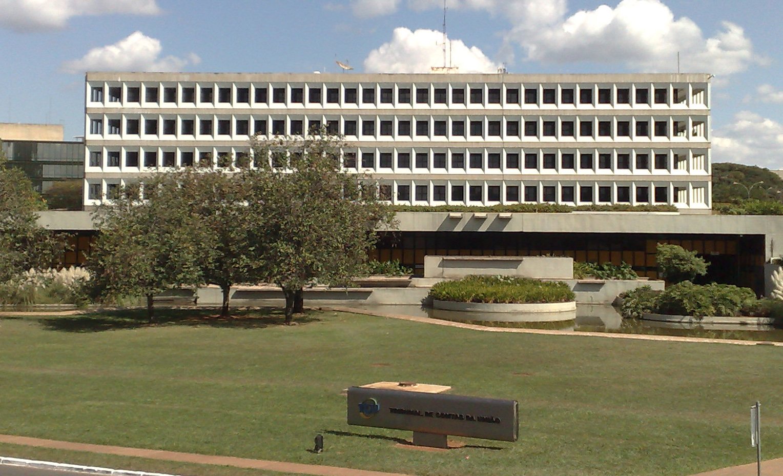Fachada do edifício-sede do Tribunal de Contas da União, em Brasília, com gramado e placa da instituição em primeiro plano