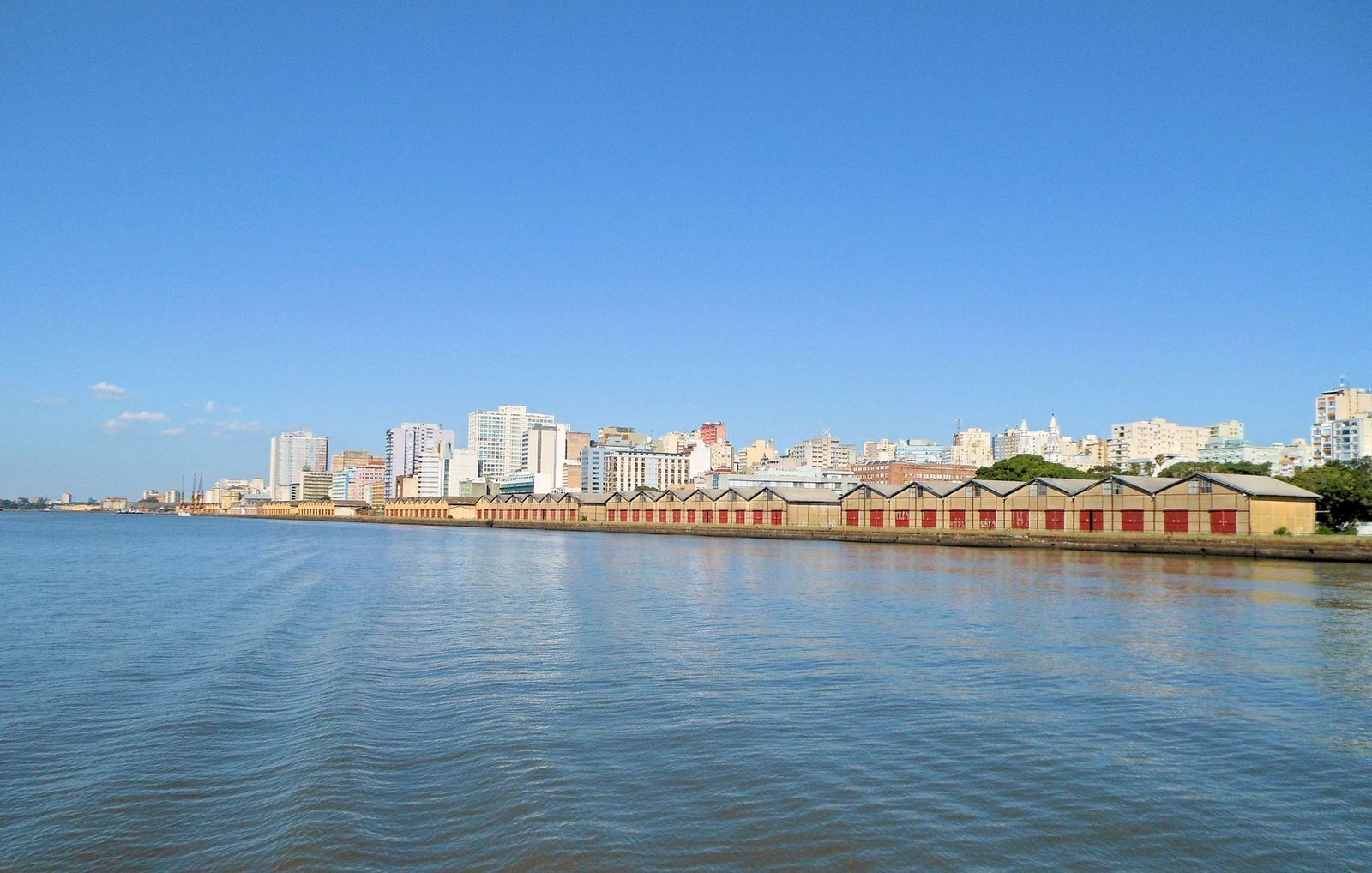Orla de Porto Alegre vista do Guaíba, com armazéns do cais e prédios do centro ao fundo