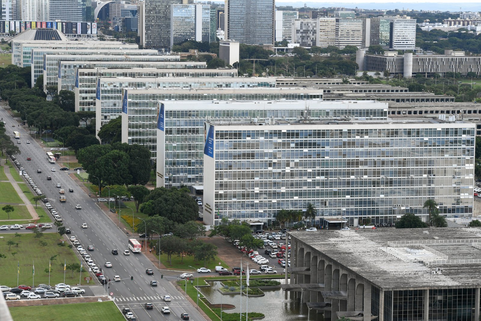 Vista aérea da Esplanada dos Ministérios em Brasília, com os blocos ministeriais em fila e o Eixo Monumental à esquerda