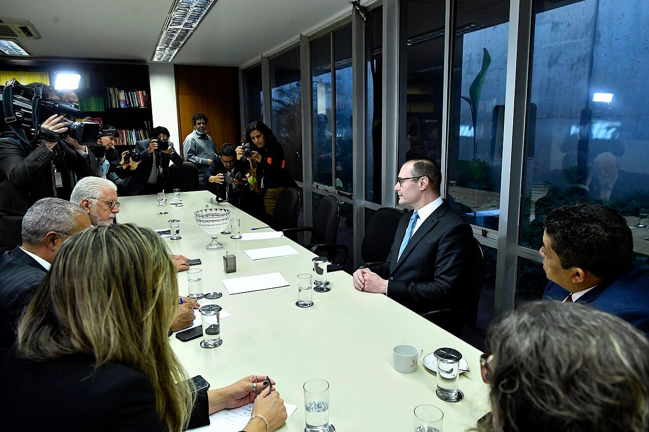 Cristiano Zanin sentado à mesa de reunião no Senado, cercado por fotógrafos, em foto de arquivo de quando ainda era advogado