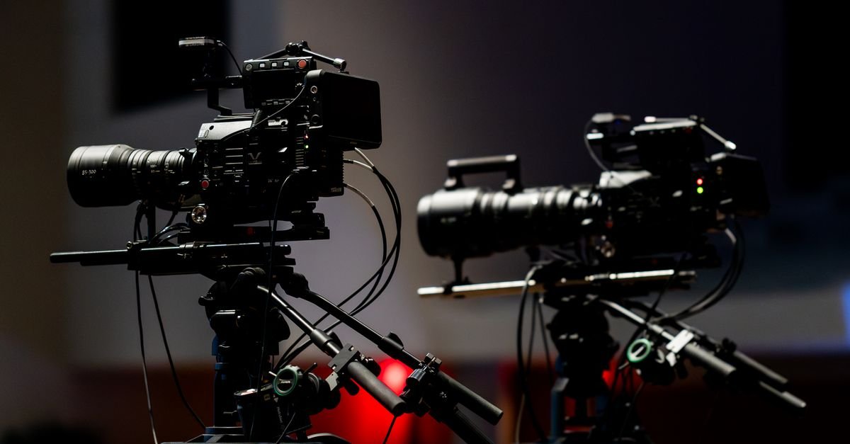 Duas câmeras profissionais de televisão posicionadas em estúdio com iluminação baixa